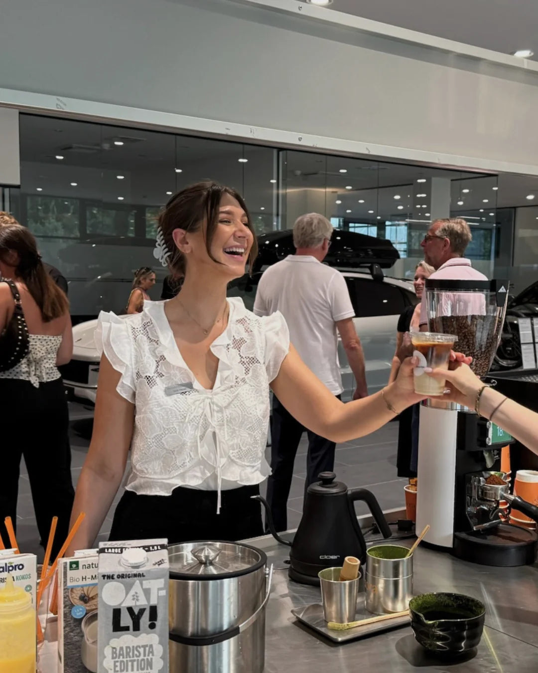 Barista reicht einer Gästin einen Iced Matcha Latte bei einem Brand Event im Showroom