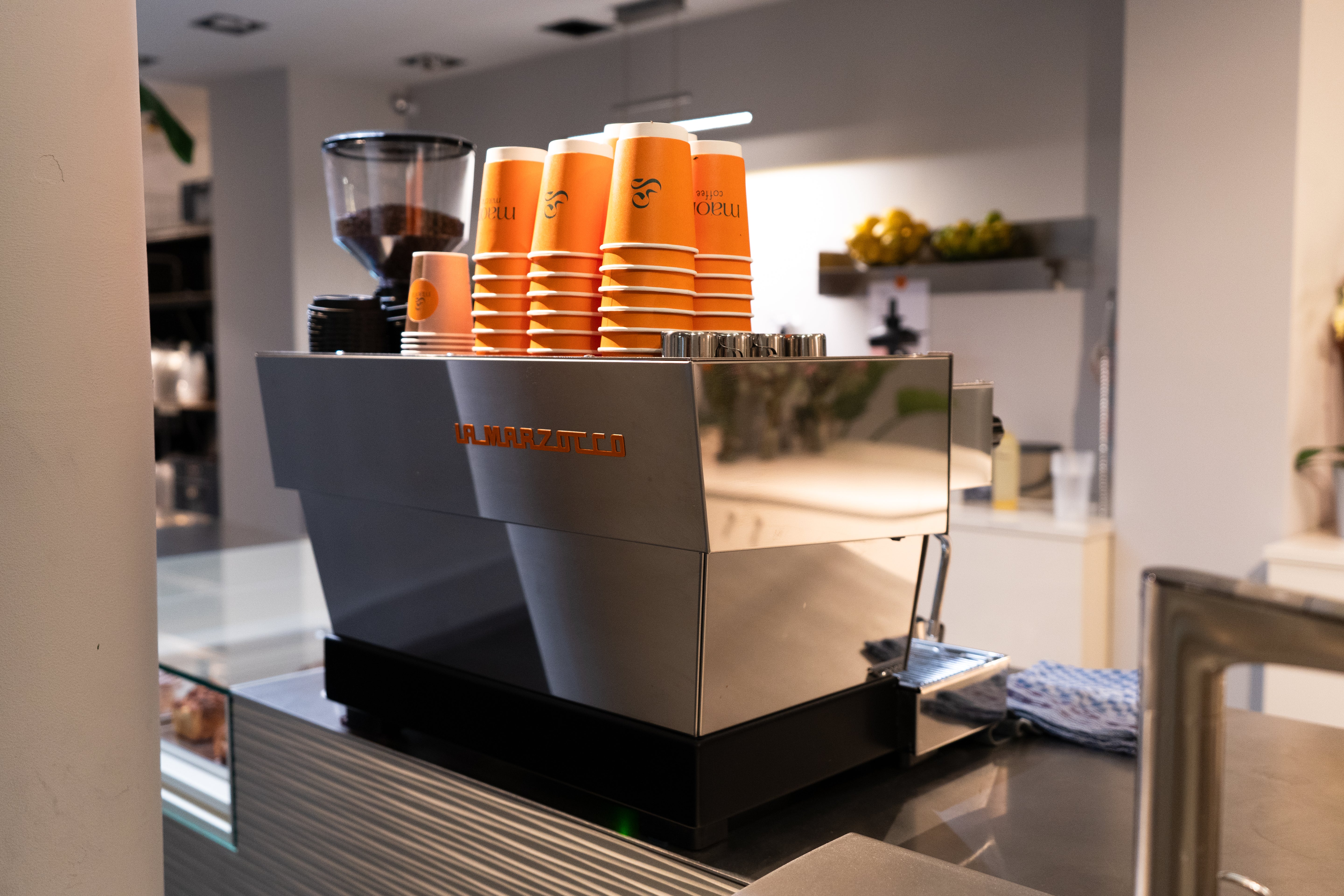 Innenansicht des Maora Cafés in Köln mit Espressomaschine, To-go-Bechern und offener Barista-Theke
