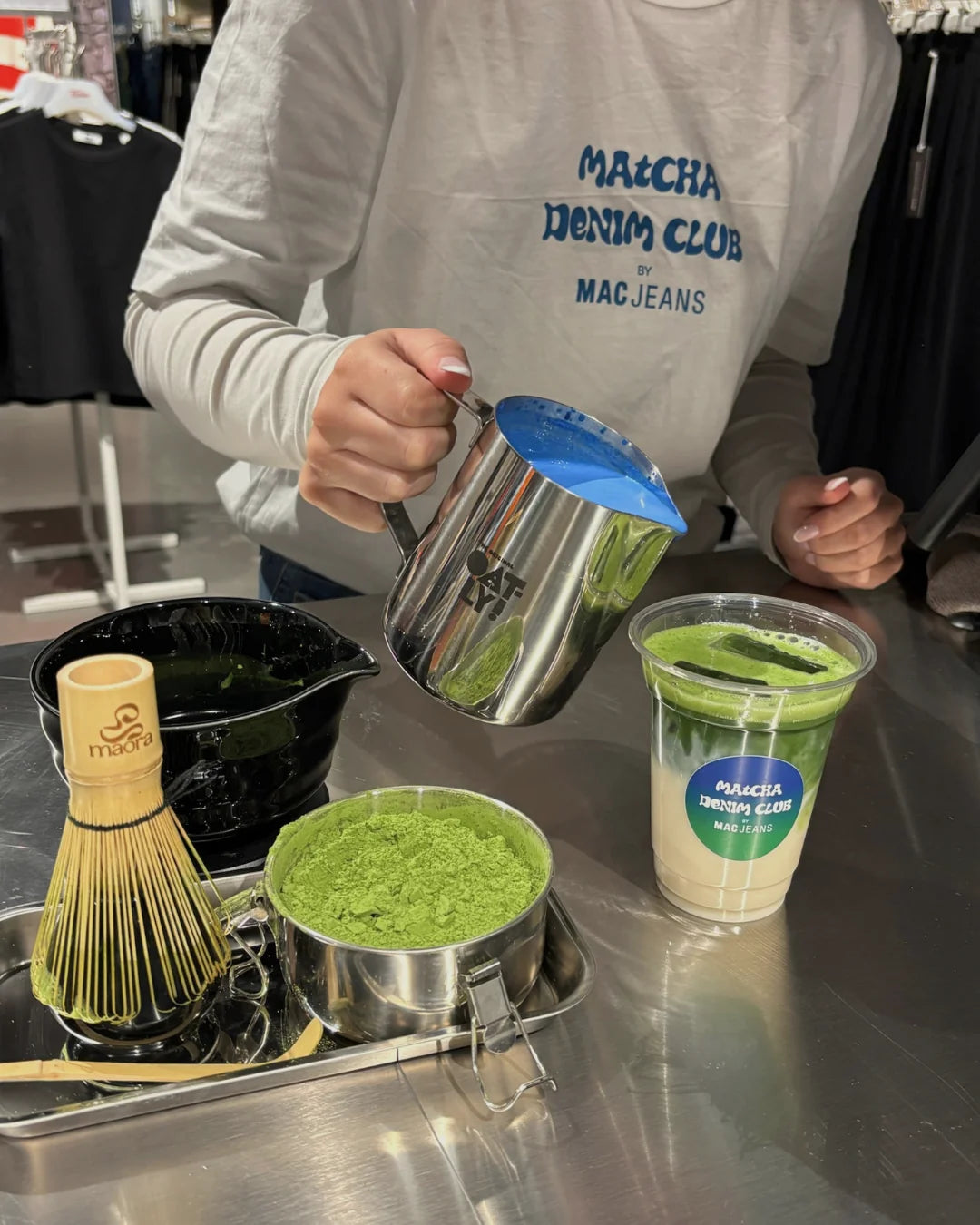 Barista gießt Milch für einen Iced Matcha Latte beim Matcha Denim Club von MAC Jeans