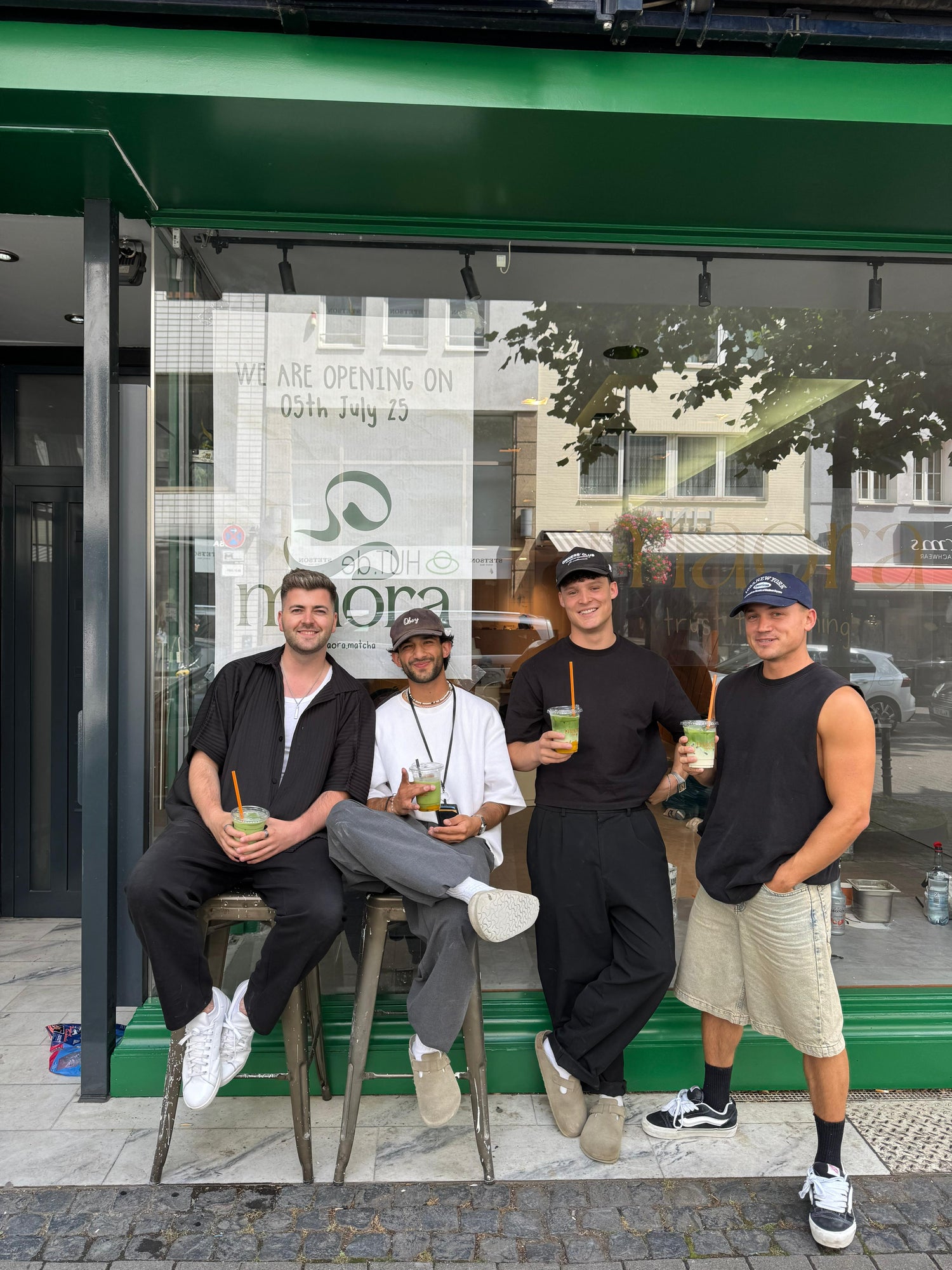 Die vier Gründer von Maora Matcha stehen vor dem Café und halten Matcha-Getränke in der Hand
